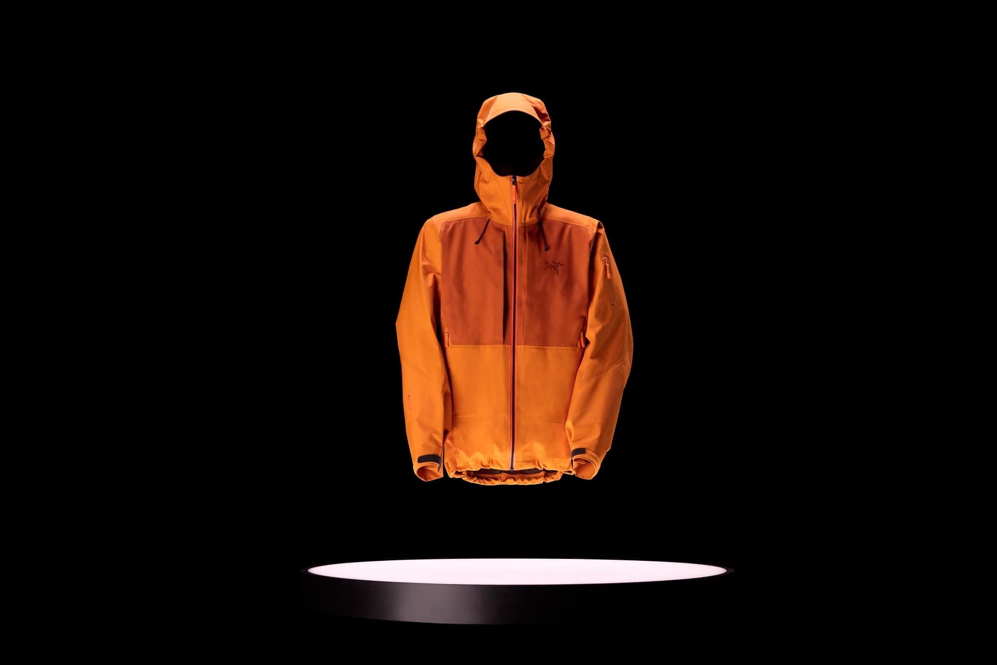Orange Arc'teryx Sperro SV Jacket displayed above a lit pedestal