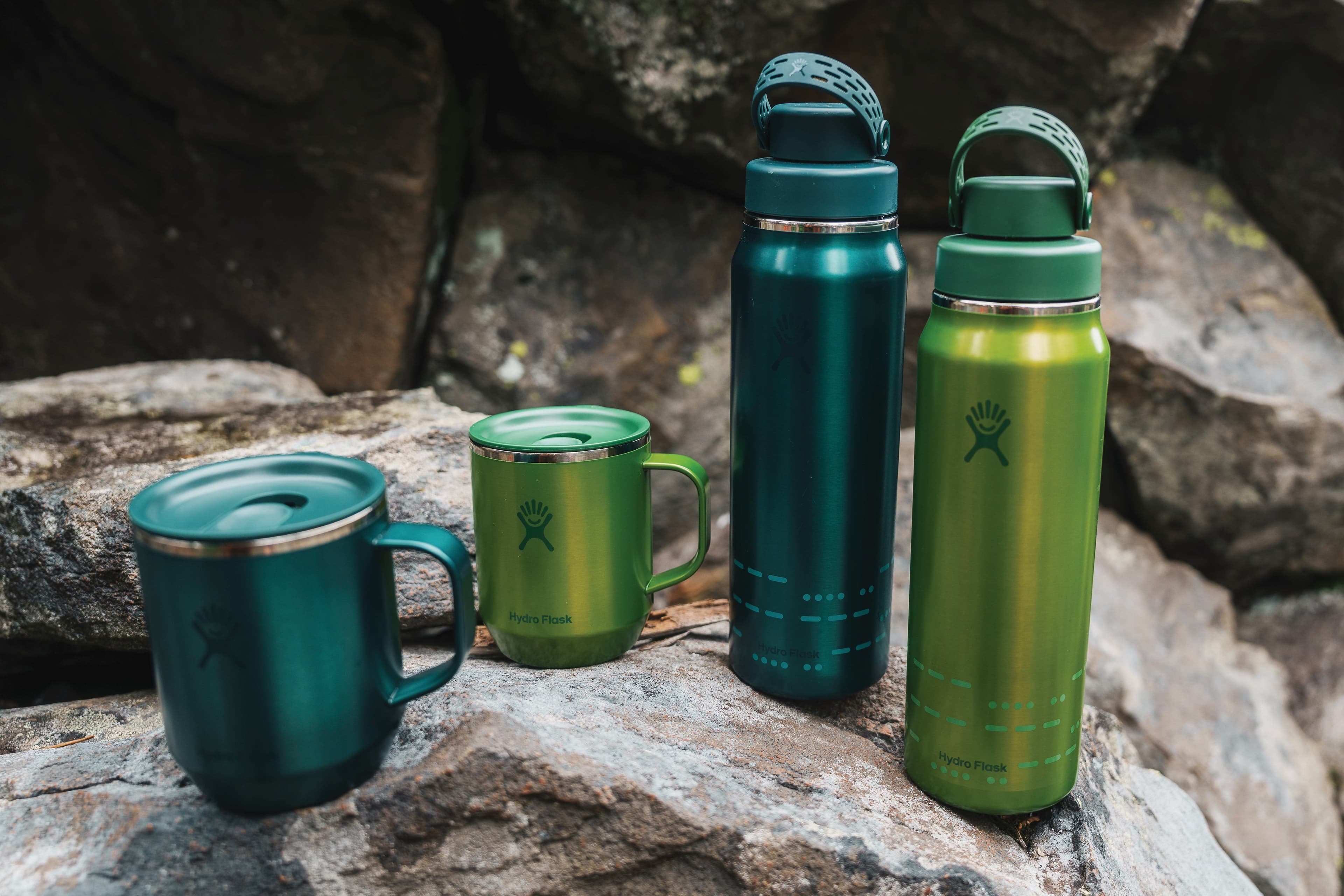 Atlas Blue and Cypress Green Hydro Flask Lightweight mugs and bottles arranged on rocks