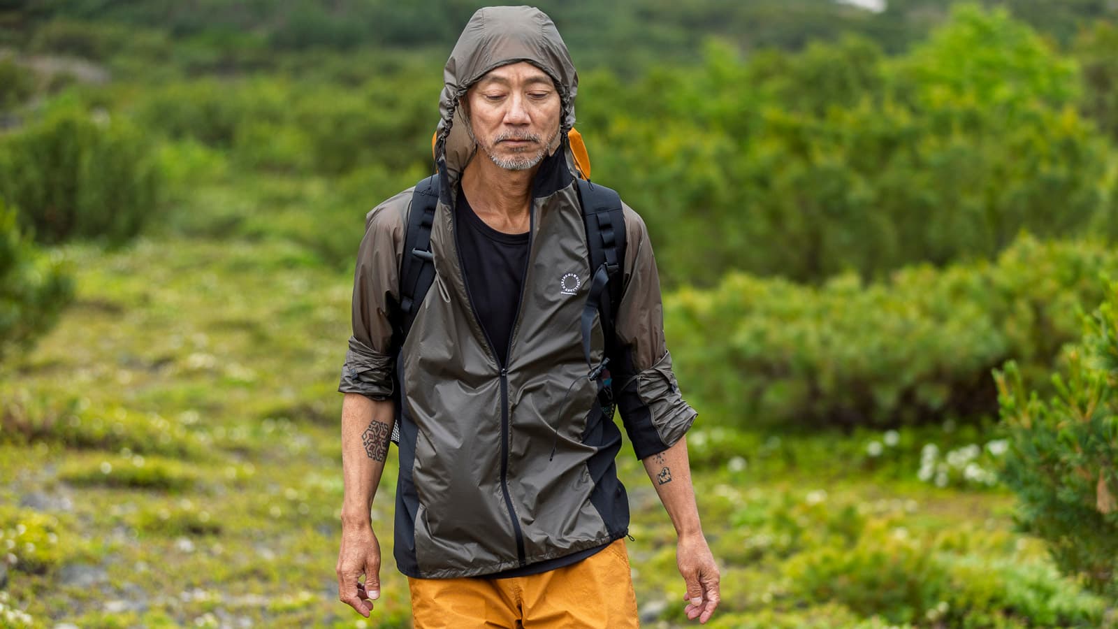 A hiker wearing the Yamatomichi Wind Zip Hoody with its hood up